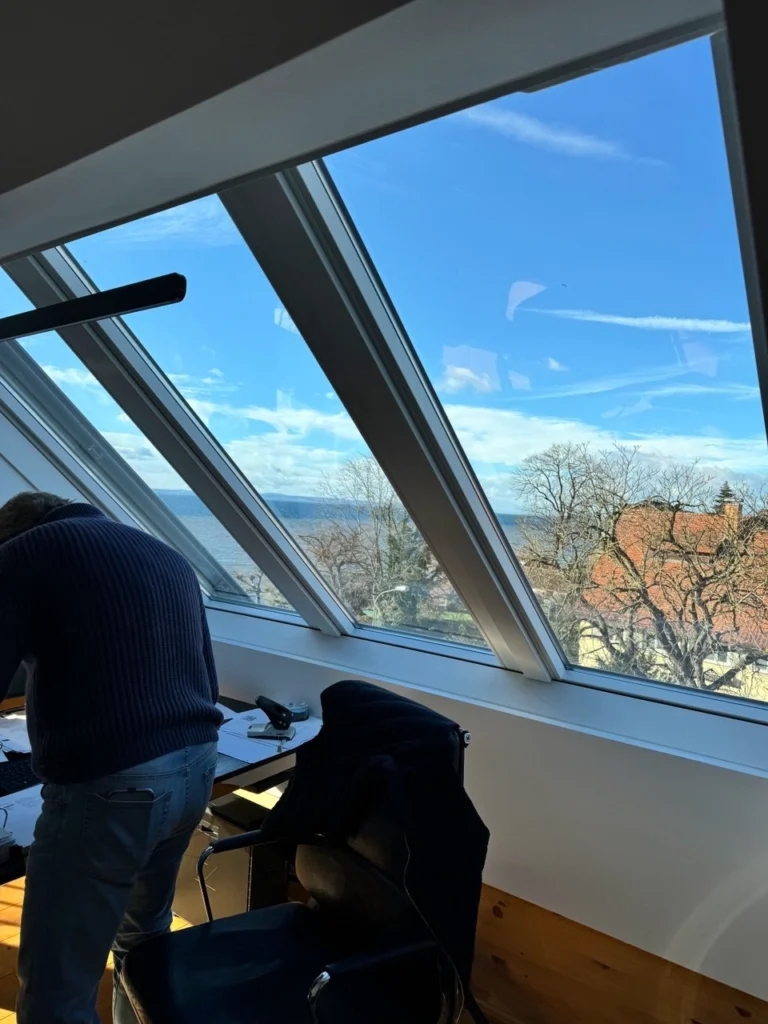 Große Dachfenster mit Blick auf das Meer in einem modernen Büro mit Holzverkleidung und minimalistischer Einrichtung.