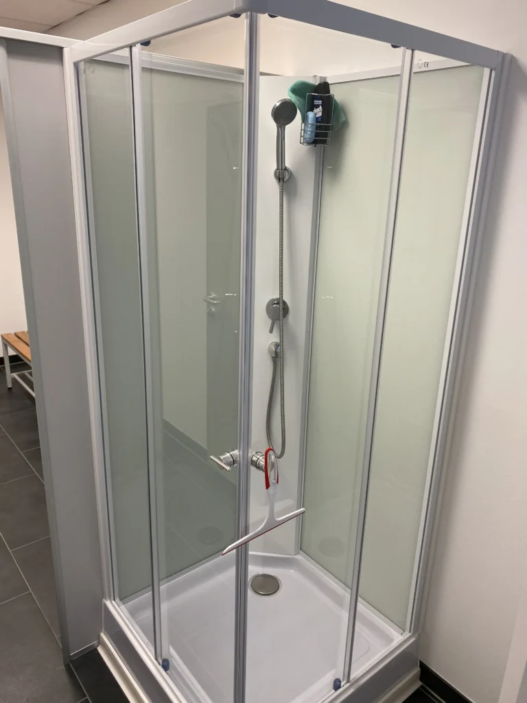 Moderne Duschkabine mit Glaswänden in einem Umkleideraum.