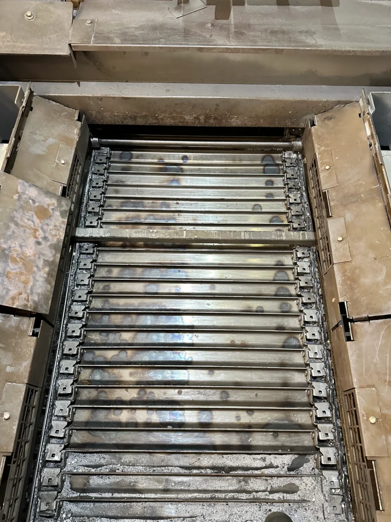 Gereinigter Schneidtisch einer Laserschneidanlage mit Oxidationsspuren und verbleibenden Metallrückständen.