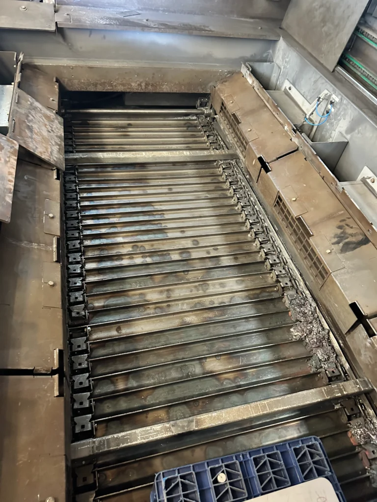 Schneidtisch einer Laserschneidanlage nach der Reinigung, mit verbleibenden Metallrückständen und Oxidationsspuren.