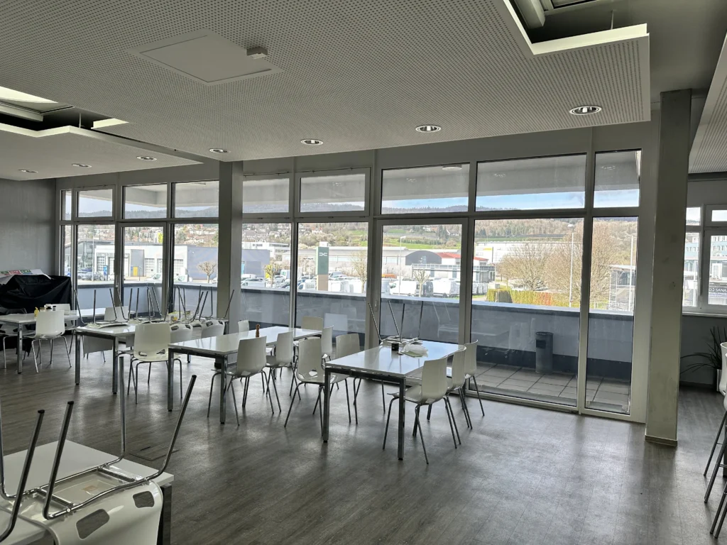 Moderner Speisesaal mit großen Fenstern, Panoramablick auf die Umgebung und Zugang zur Terrasse.