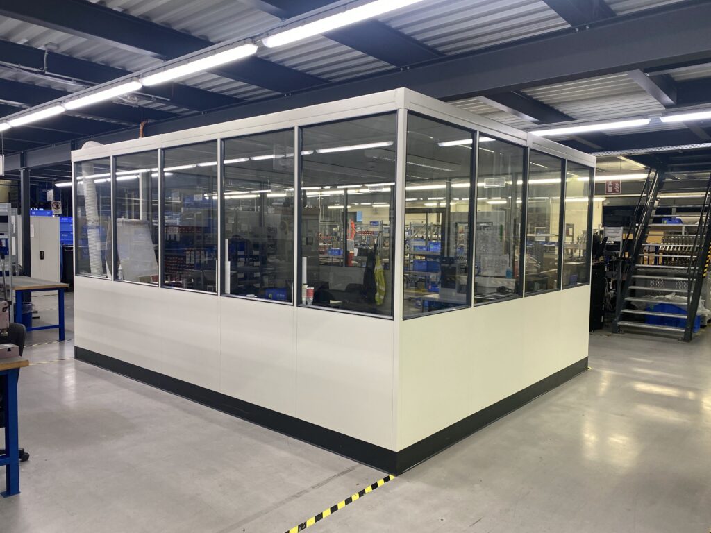 Modulares Büro in Industriehalle mit Glasscheiben Modulares Büro in einer Industriehalle mit großen Glasscheiben für optimale Sicht und Integration in die Produktionsumgebung.